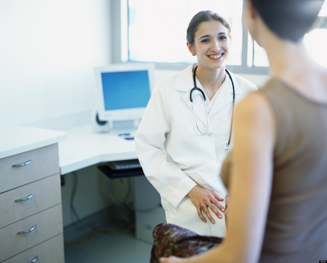 Young female doctor sitting in exam room with female patient